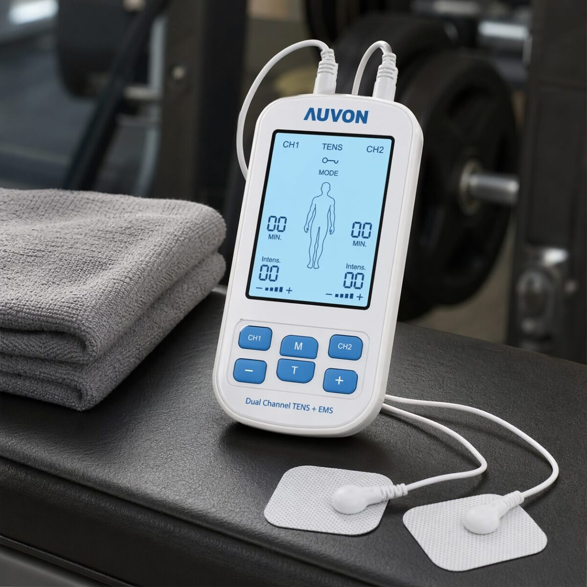AUVON Dual Channel TENS EMS unit with blue LCD screen and electrode pads on gym bench