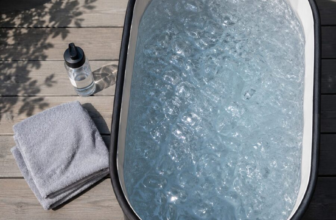 Portable cold plunge tub filled with ice water on wooden patio deck