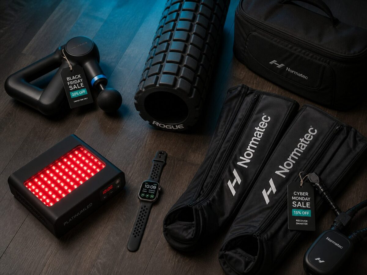 Recovery gear flat lay with Memorial Day sale tags - massage gun, foam roller, compression boots on dark gym floor