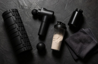Recovery gear flatlay including foam roller massage gun lacrosse ball and supplements on slate gym floor