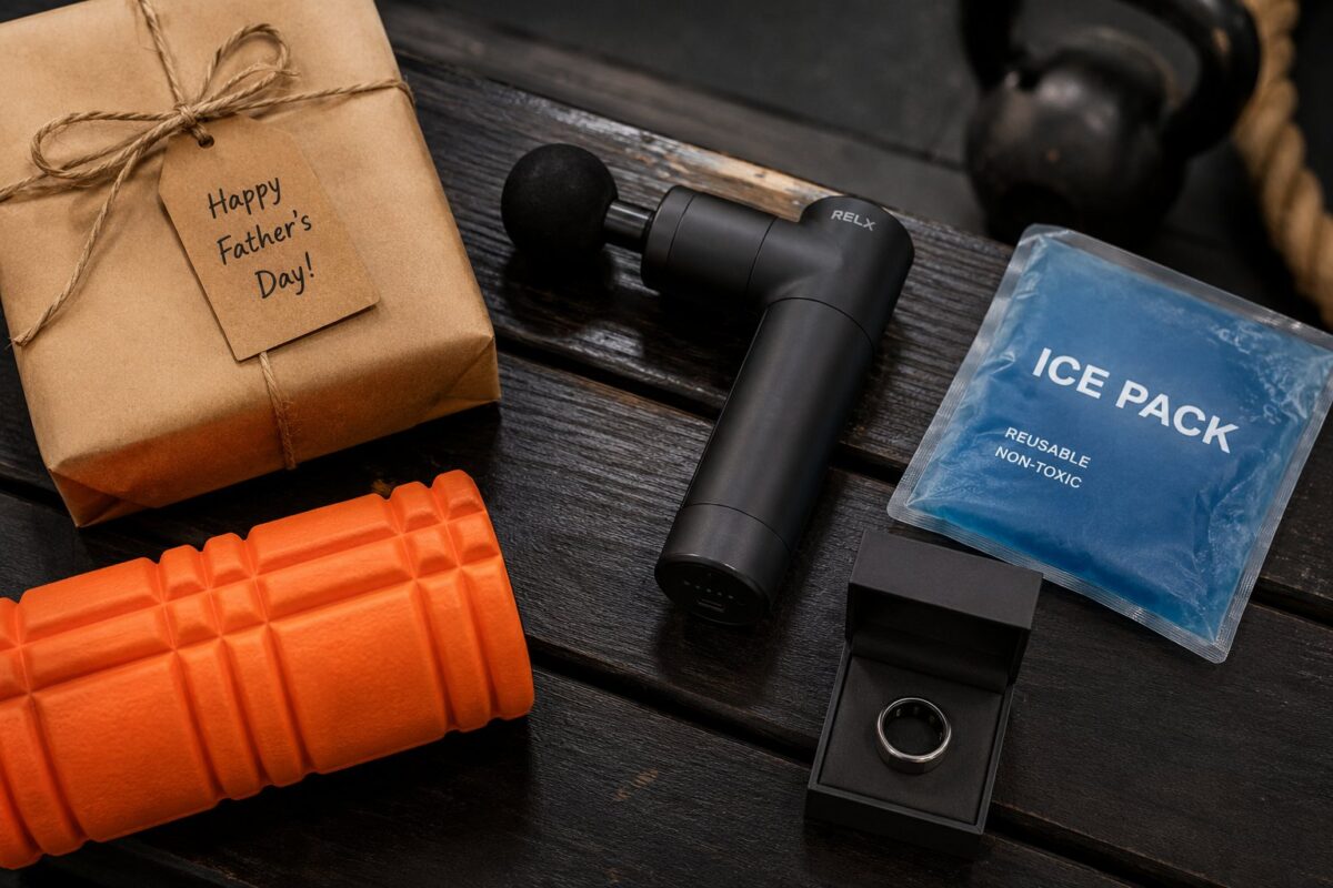 Massage gun, gel ice pack, foam roller and smart ring gift box on a dark gym bench