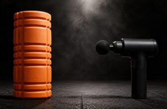 Orange foam roller and black percussion massage gun side by side on a gym floor