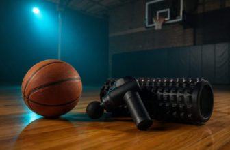 Basketball on a hardwood gym floor next to a black massage gun and foam roller in moody lighting